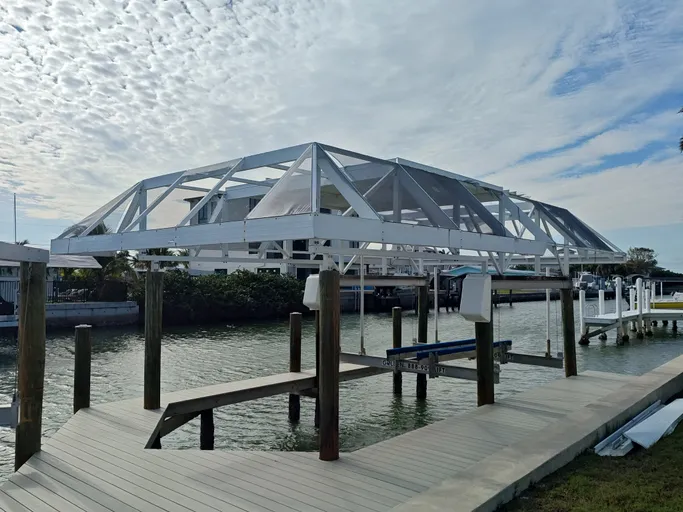 A large white structure is sitting on top of a dock next to a body of water.