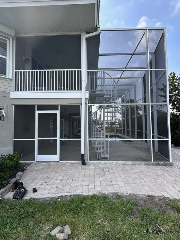 A screened in porch with stairs leading up to the second floor of a house.