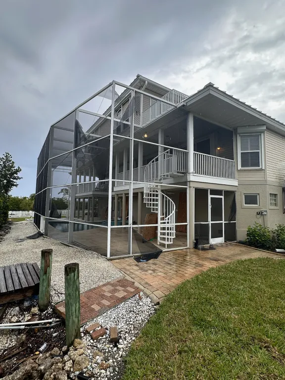 A large house with a screened in porch and a spiral staircase.