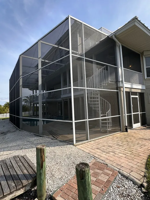 A large house with a screened in porch and a spiral staircase.