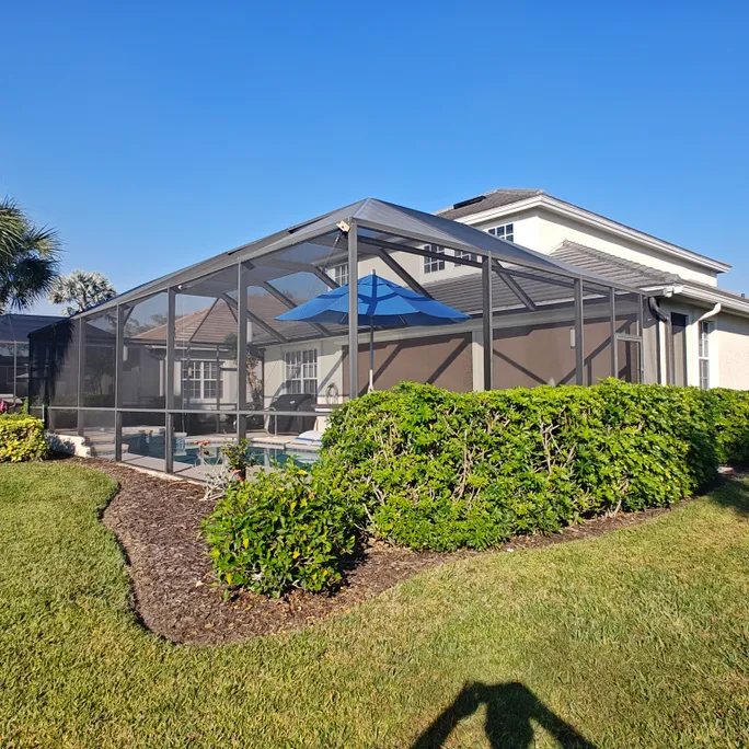 A house with a screened in pool area and a blue umbrella