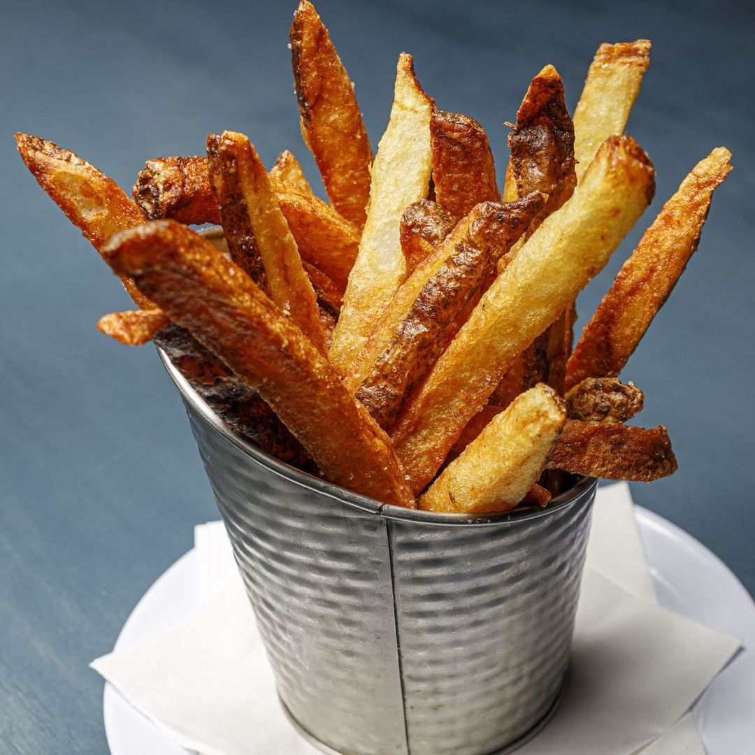 A metal bucket filled with french fries on a plate
