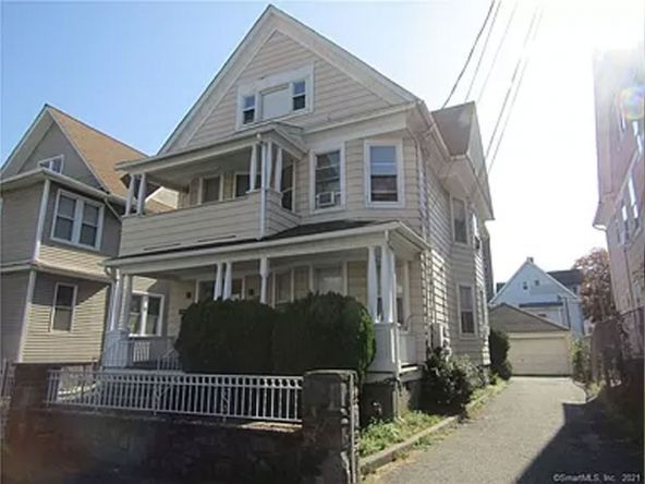 A large house with a large porch is sitting on the corner of a street.