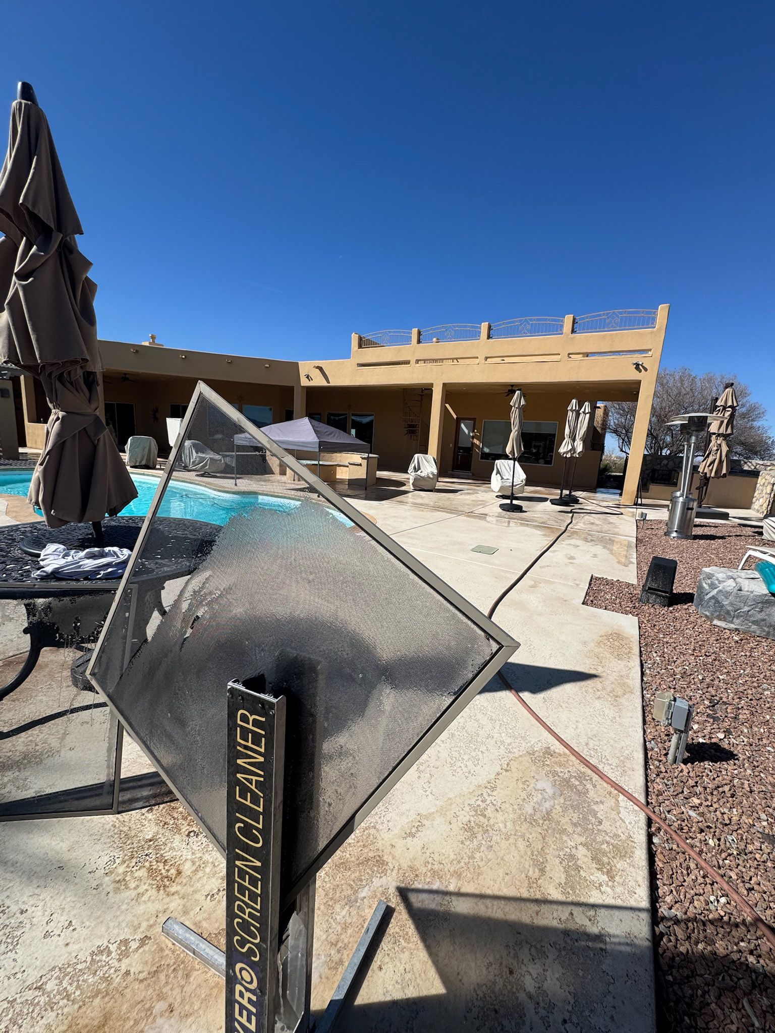 A large house with a swimming pool and umbrellas in front of it.