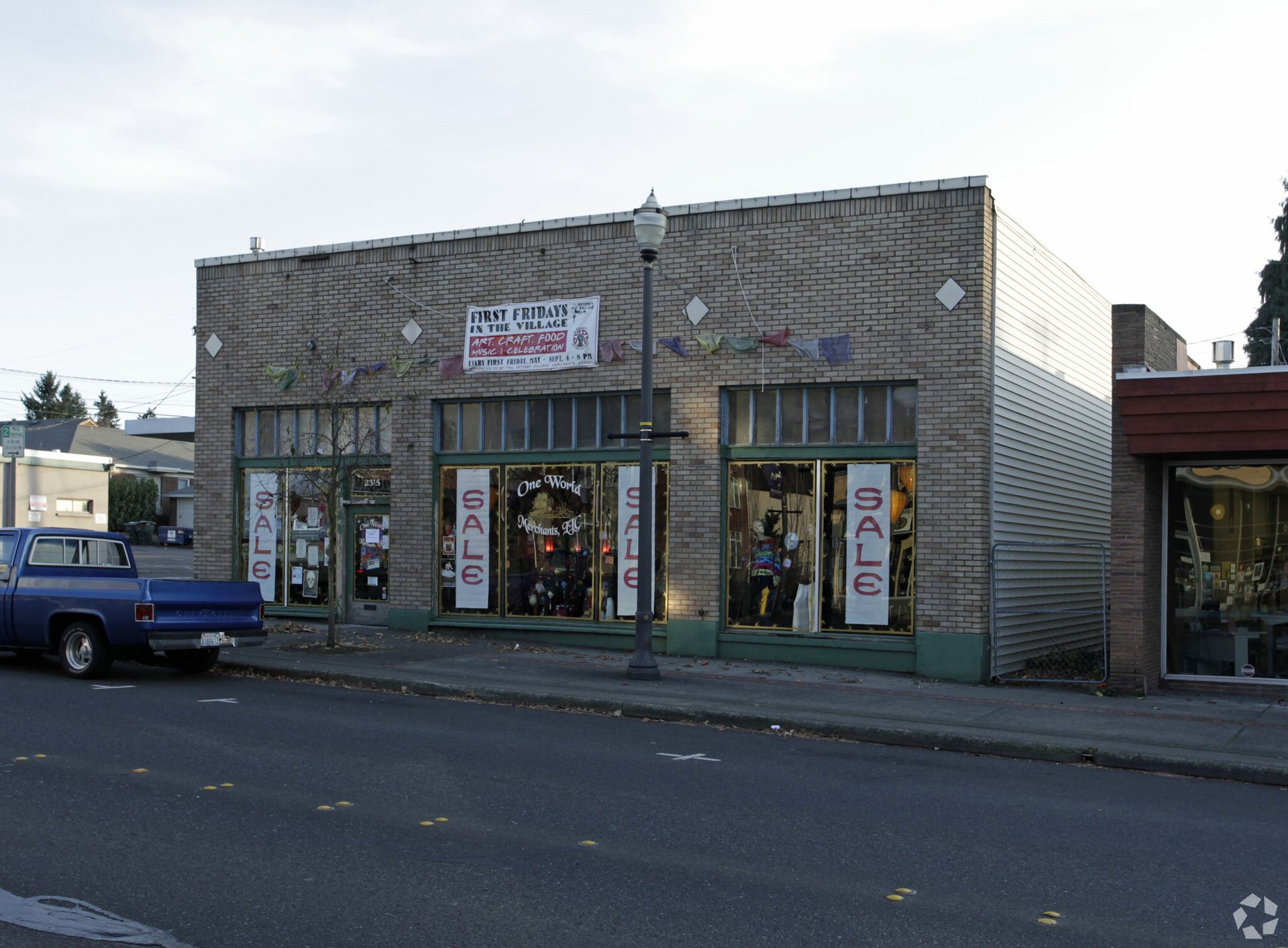 A blue truck is parked in front of a building that says sale
