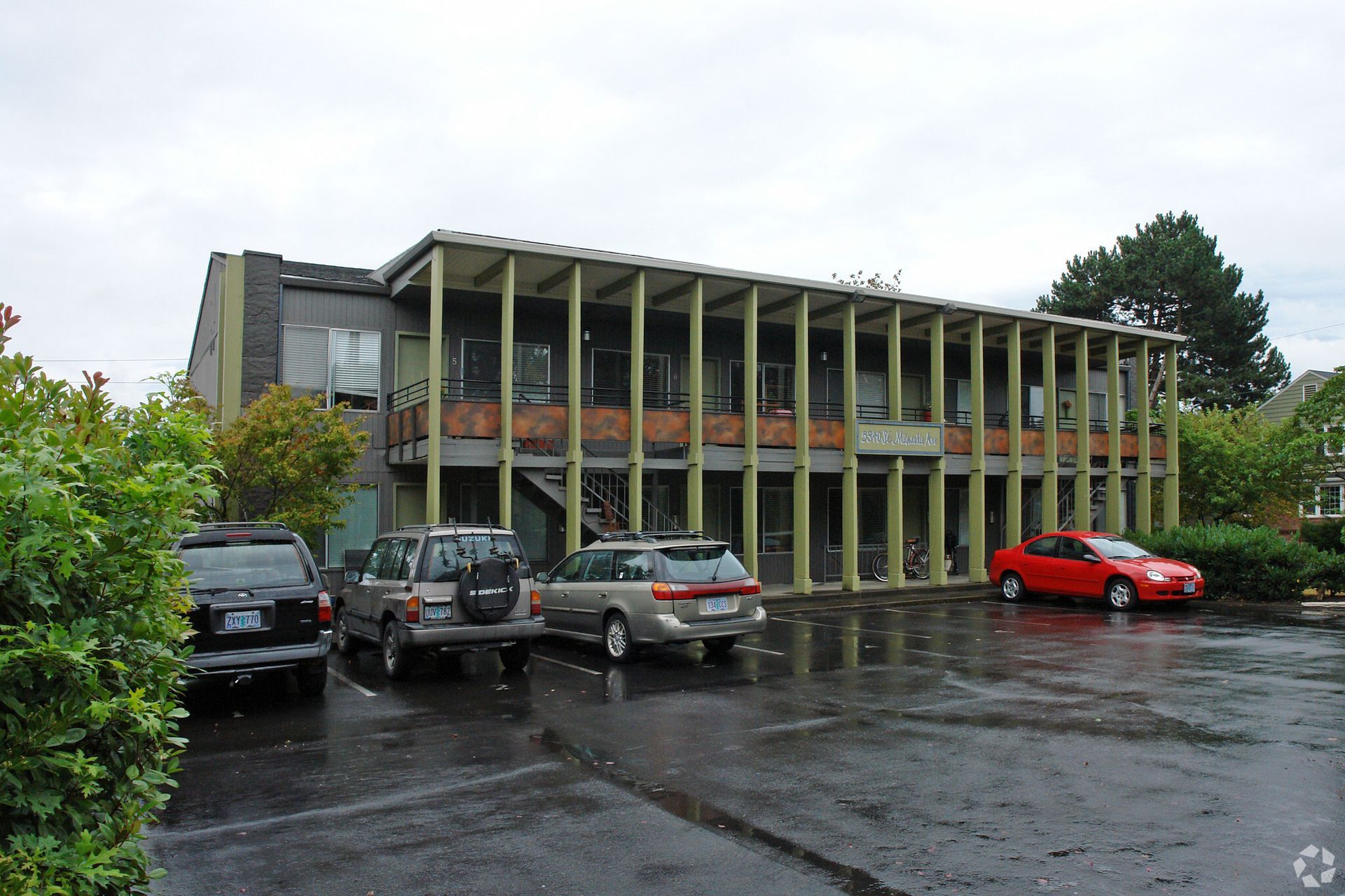 A building with cars parked in front of it on a rainy day
