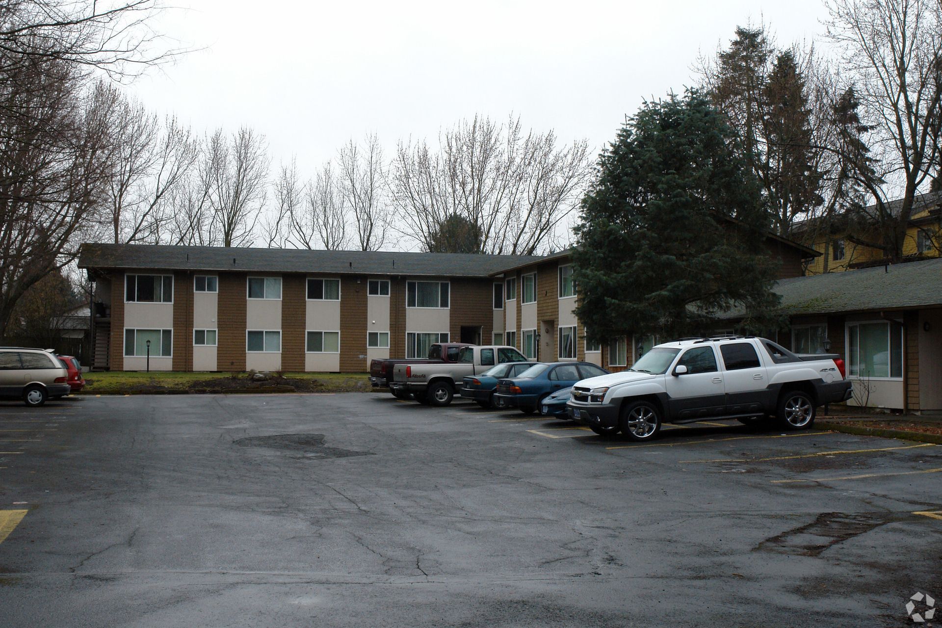 A row of cars are parked in front of a building.