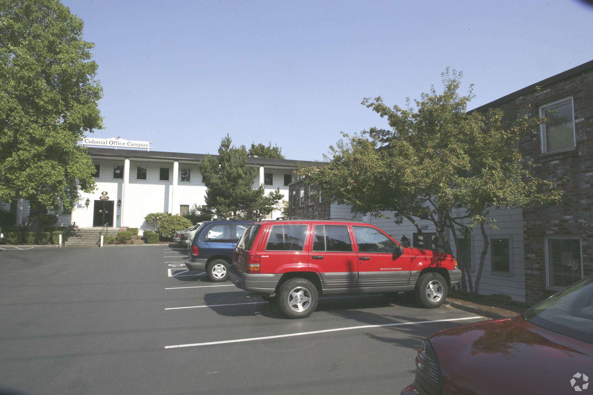 A red suv is parked in a parking lot in front of a building