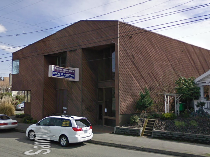A white minivan is parked in front of a large building