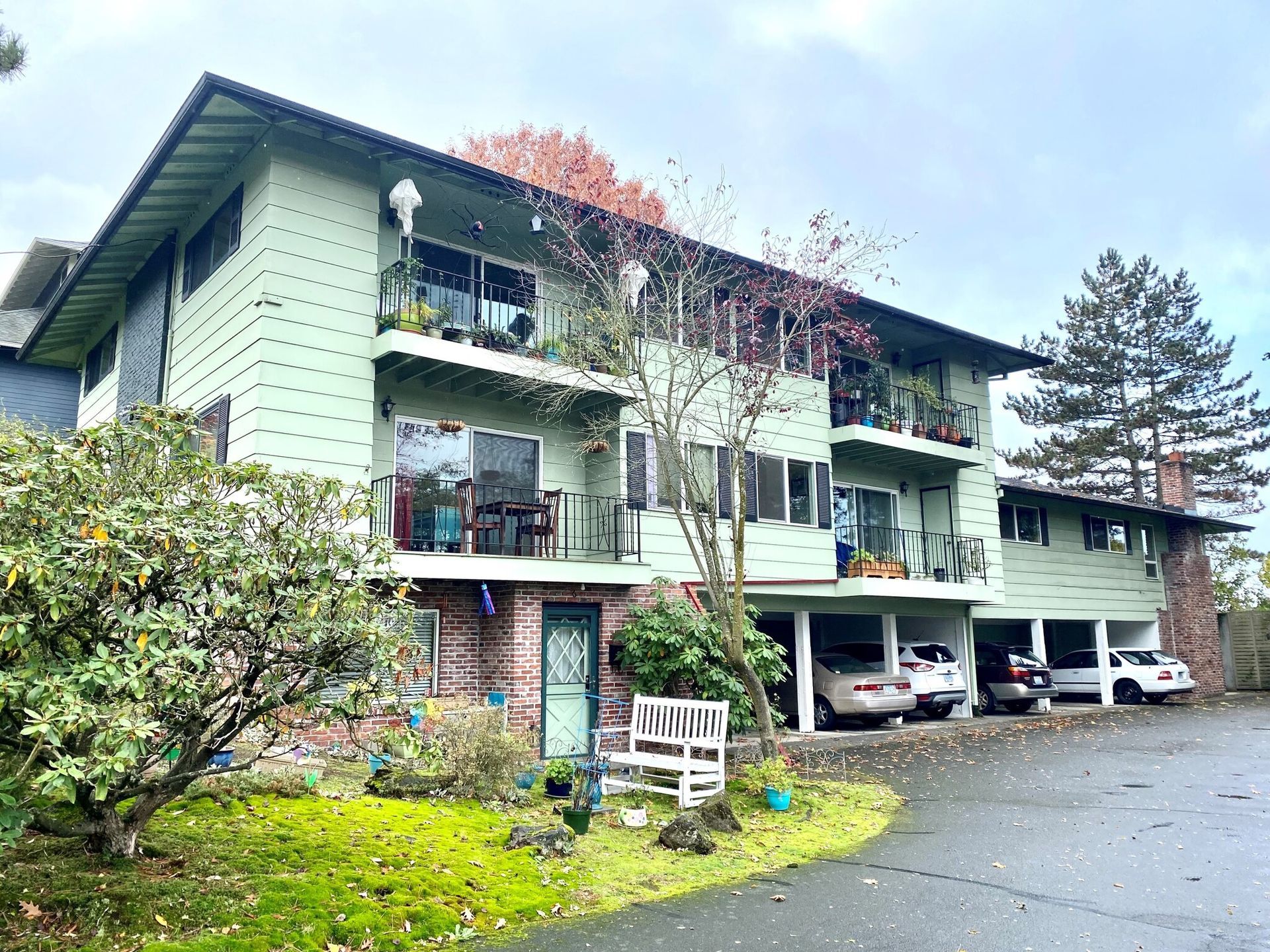 A large green apartment building with cars parked in front of it.