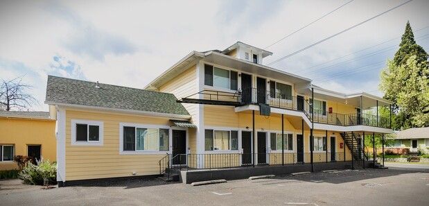 A yellow house with a white picket fence around it