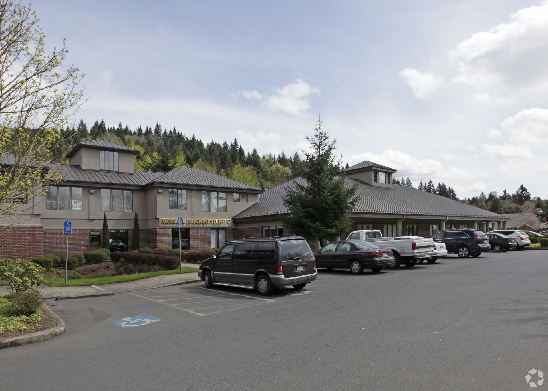 A row of cars are parked in front of a large building.