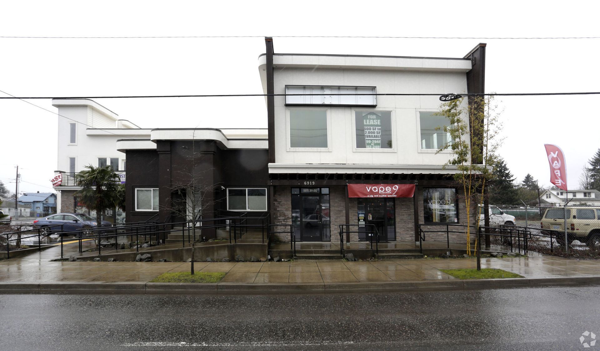 A building with a red sign on the front of it is on the side of the road.