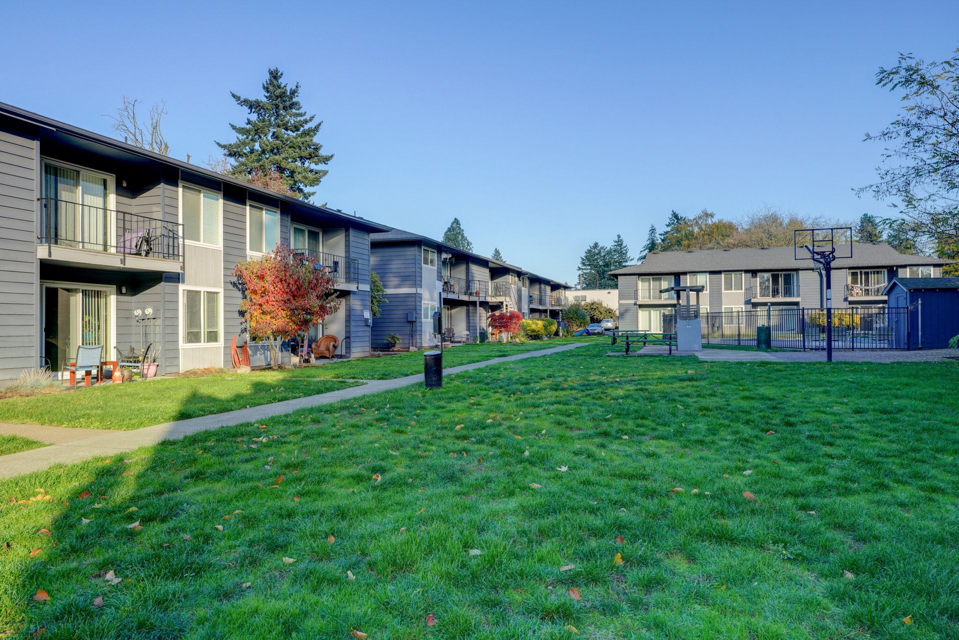A row of apartment buildings with a large lawn in front of them.