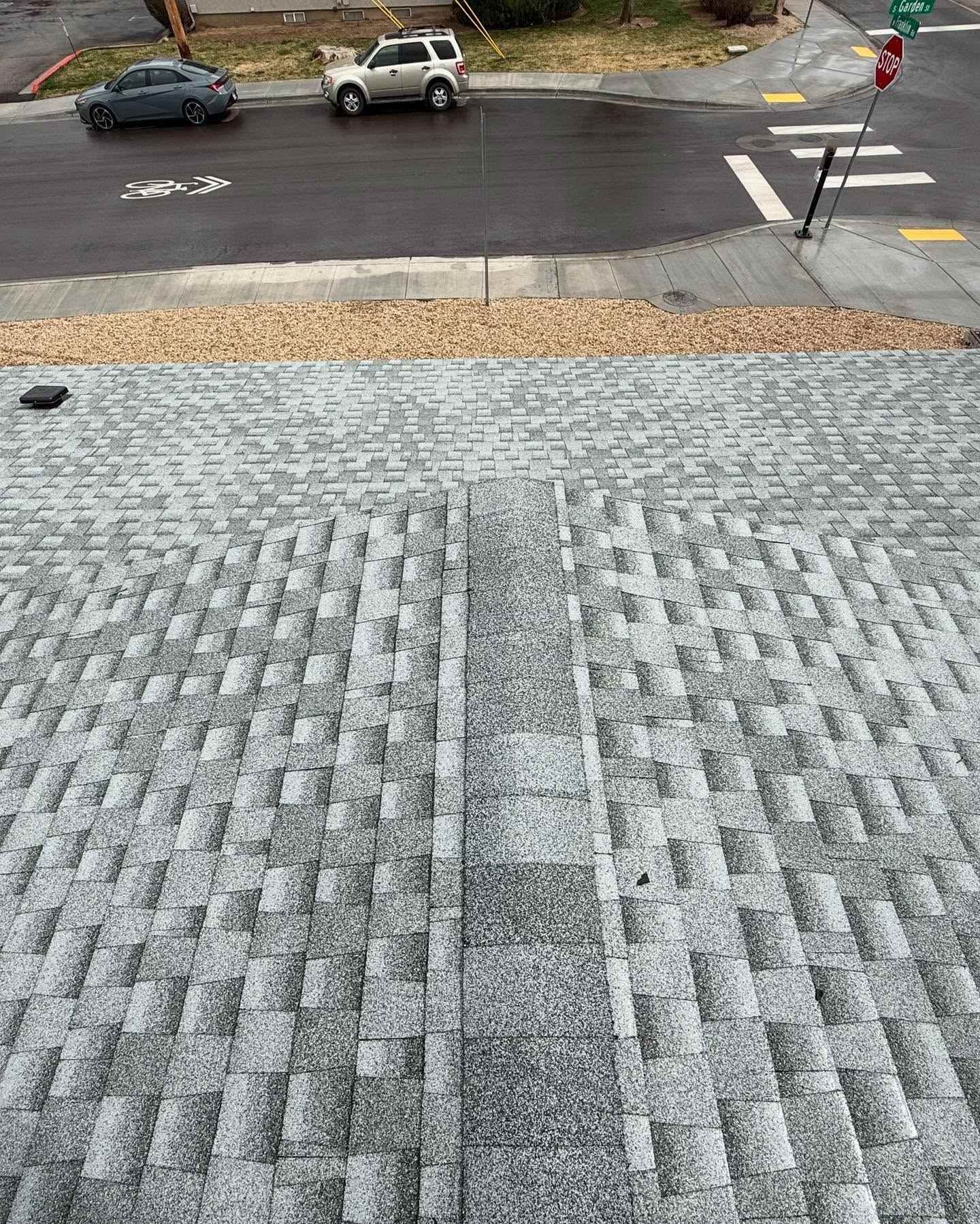 Steep textured stone walkway leading to a street with parked cars and a sidewalk crossing.