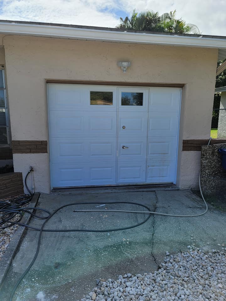 A white garage door is sitting in front of a house.