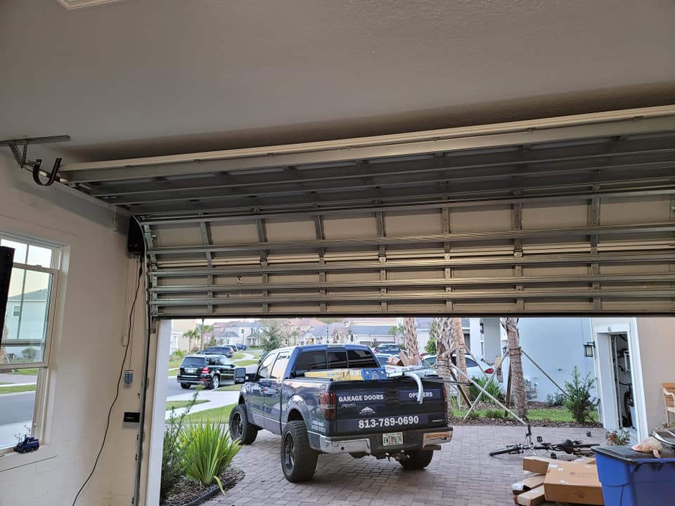 A truck is parked outside a garage with the door open.