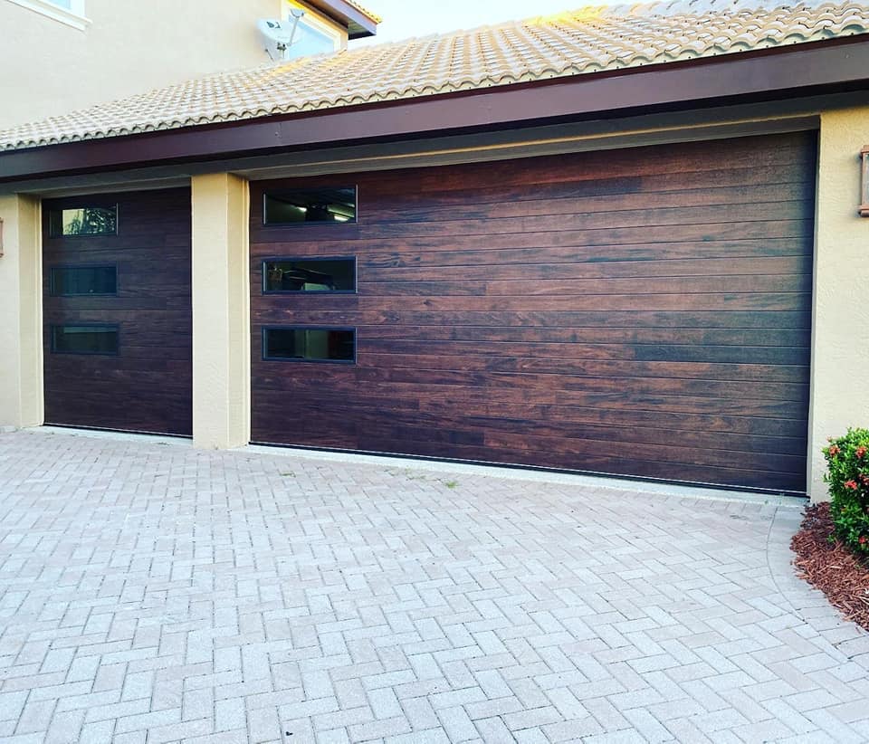 A wooden garage door with a brick driveway in front of it