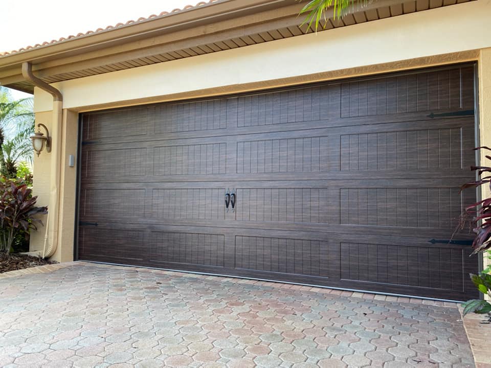 A large brown garage door is sitting in front of a house.