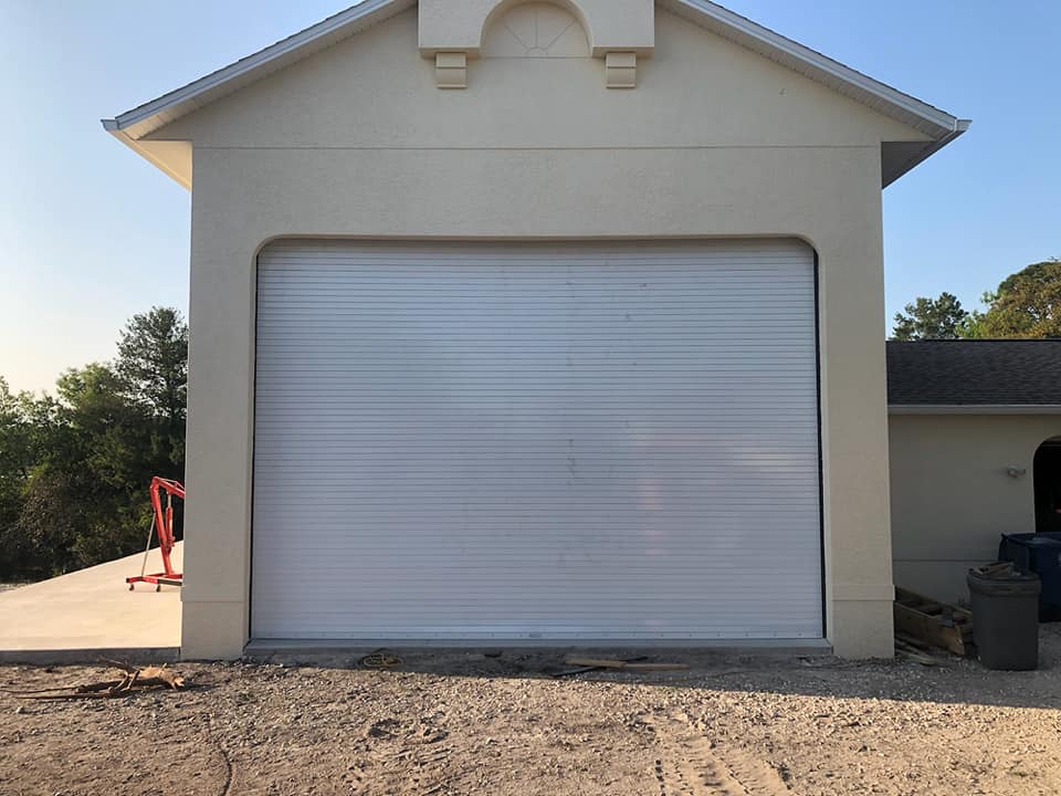 A white garage door is closed in front of a house