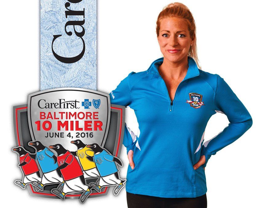 A woman is standing next to a medal for the baltimore 10 miler