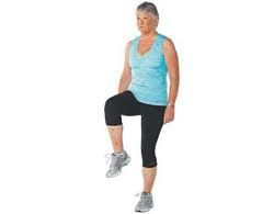 Woman in workout clothes lifting her knee, indoors.