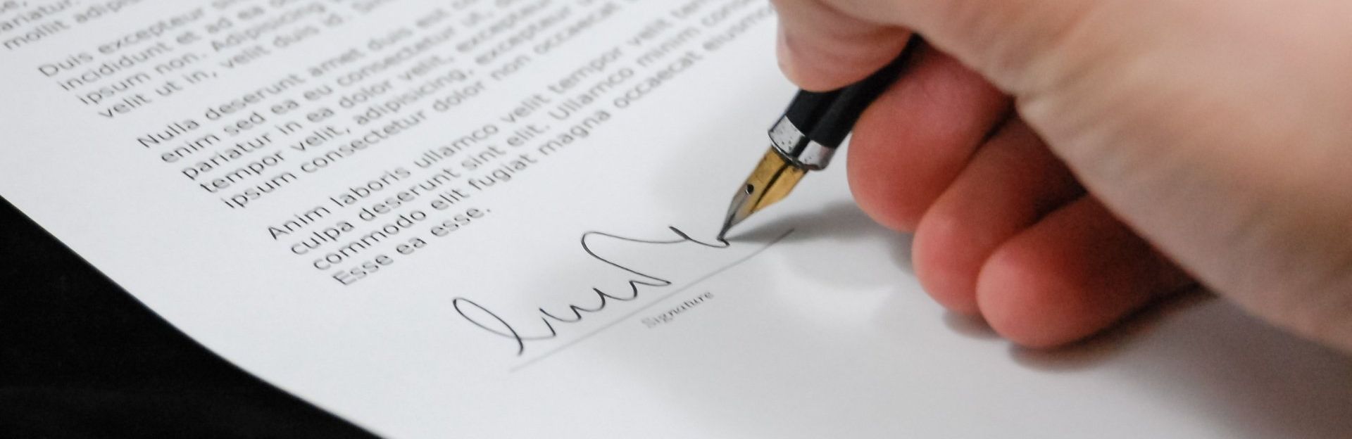 Close-up of a hand signing a formal document with a fountain pen, symbolising agreement, legal commitment, or contract finalisation.