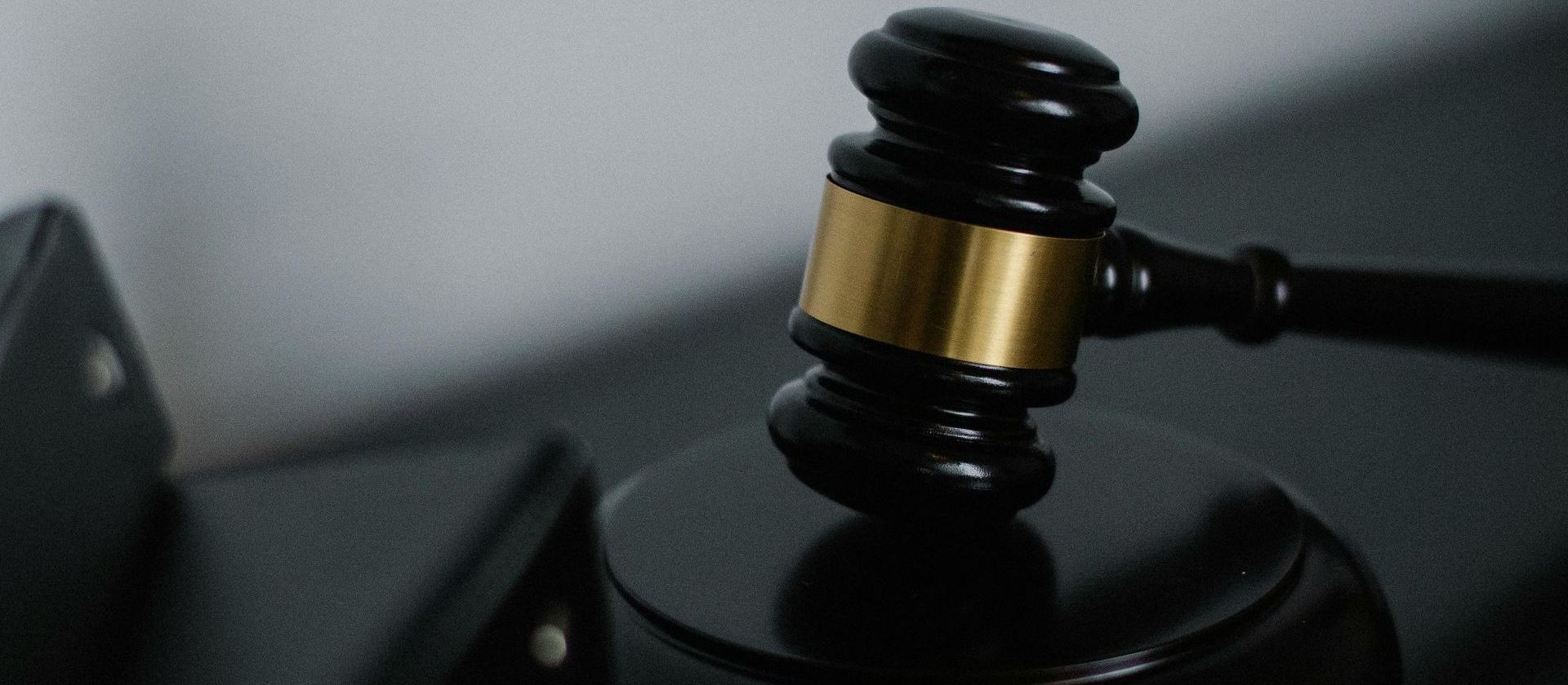 Close-up of a black judge's gavel with a gold band resting on a sounding block, symbolising justice and legal authority.