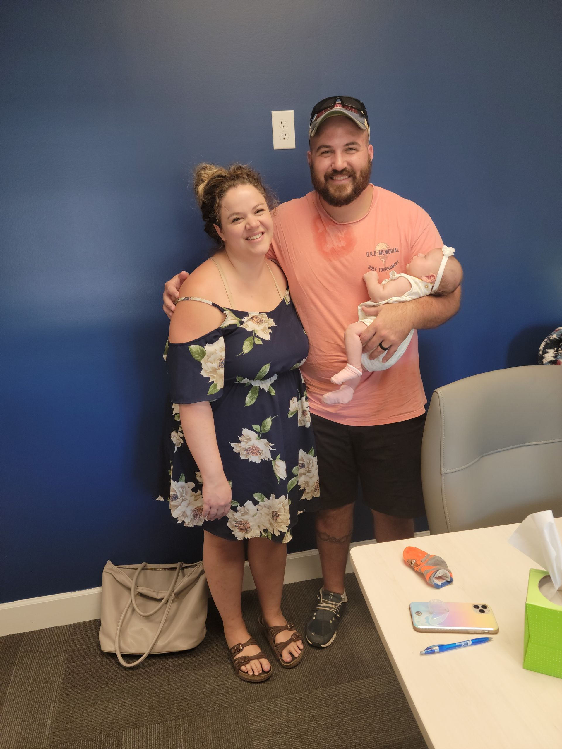 A man and woman are holding a baby in a room.