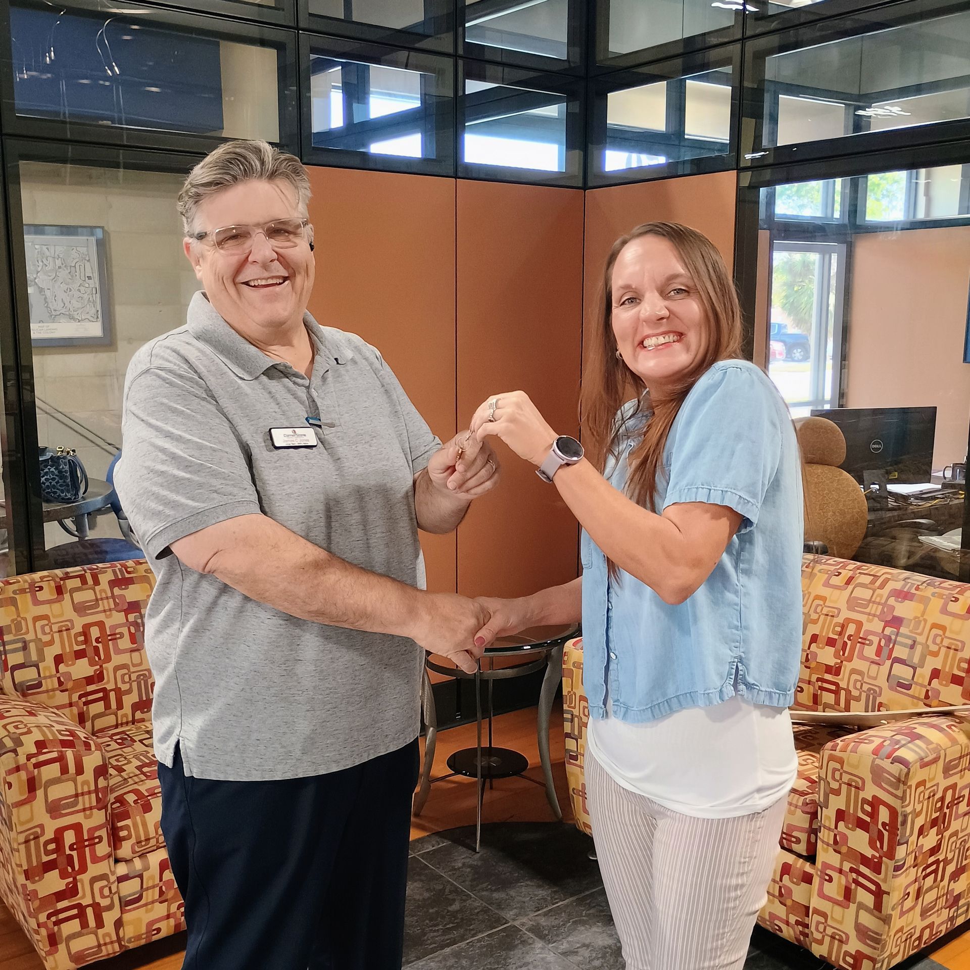 A man and a woman are shaking hands in a living room.