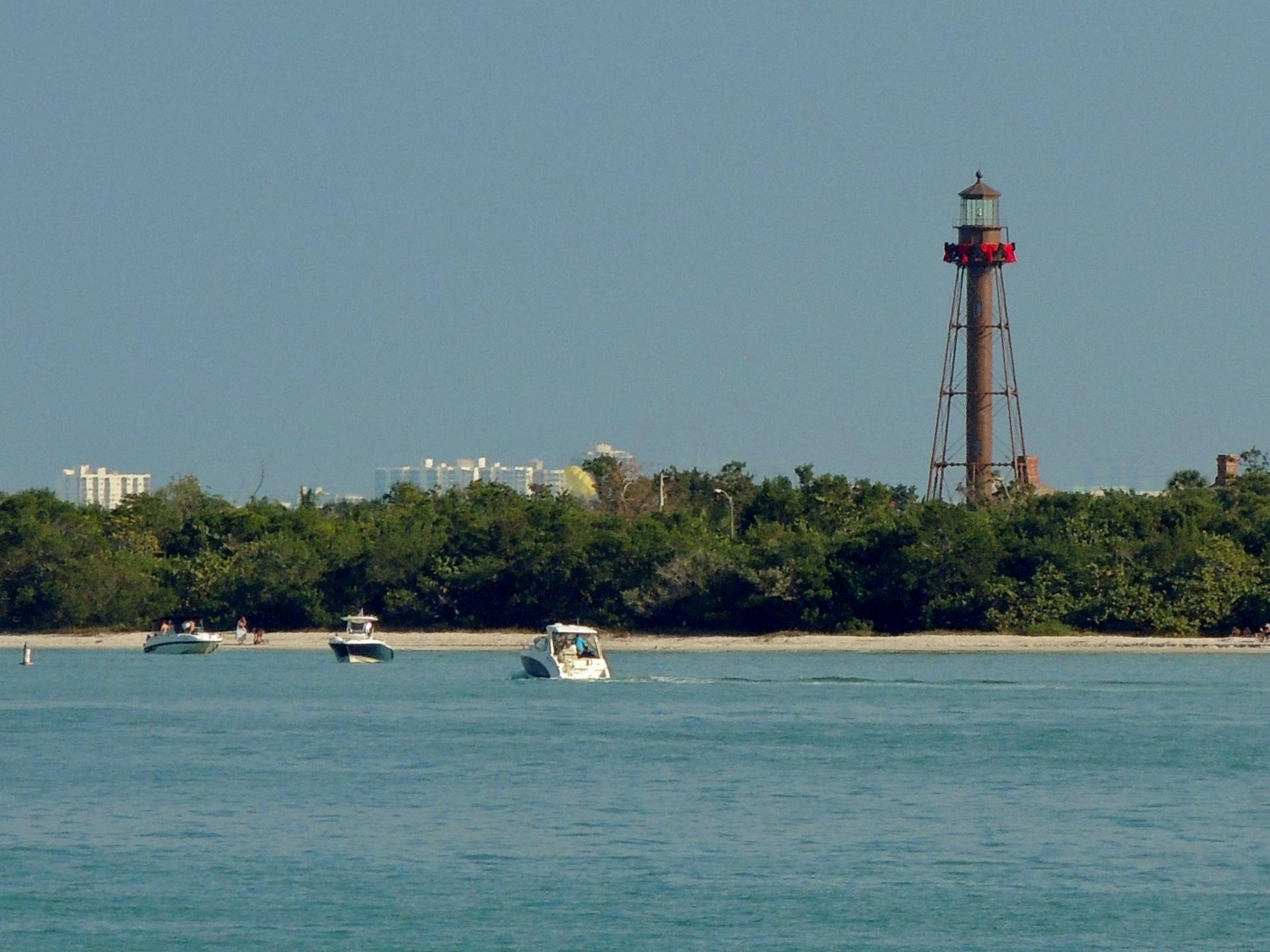 A lighthouse in the distance with boats in the foreground