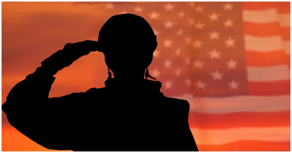 A silhouette of a soldier saluting in front of an american flag.