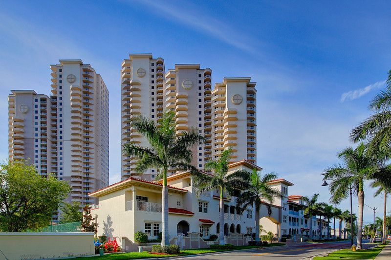 A row of tall buildings with palm trees in front of them