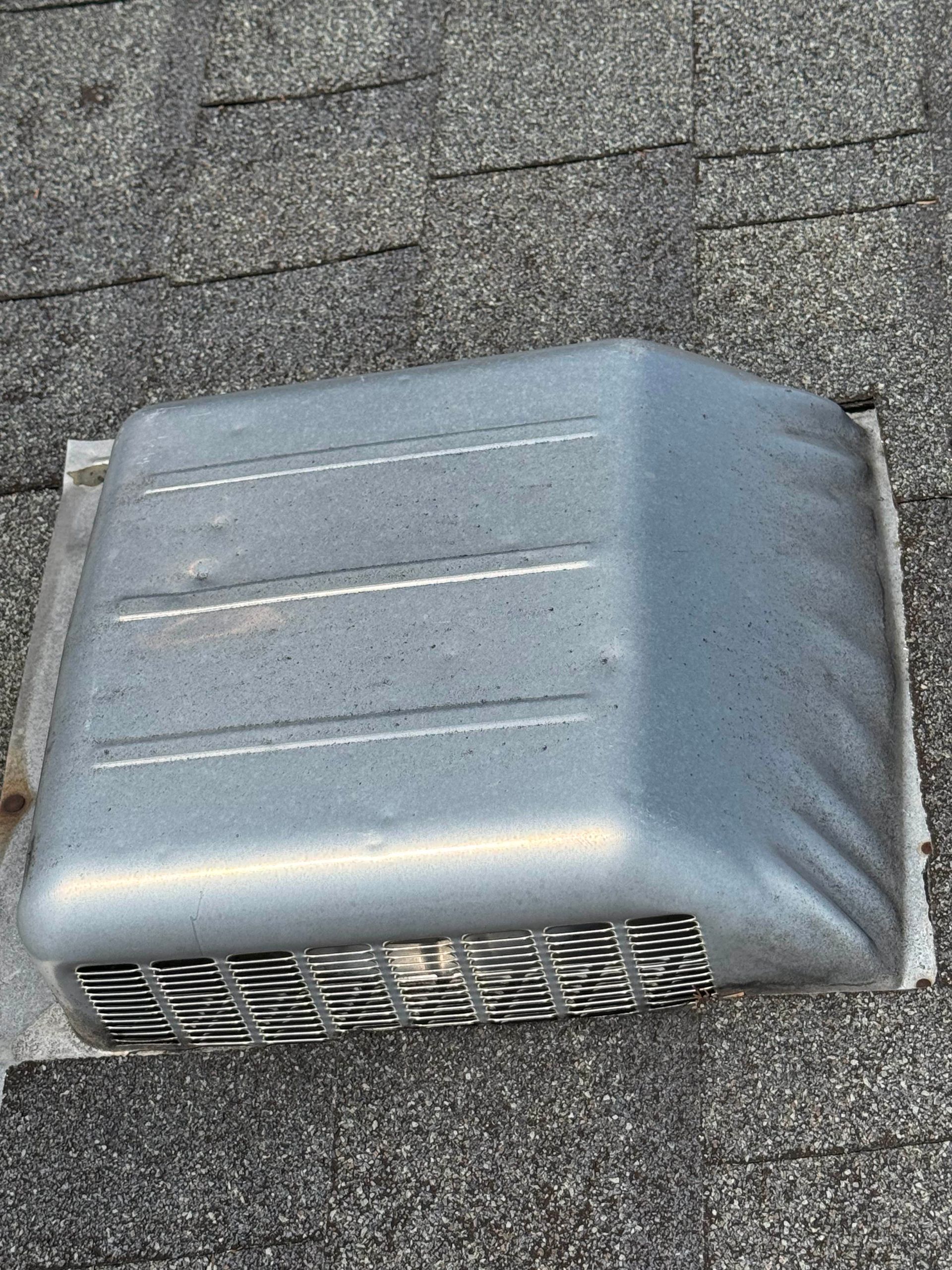 Metal roof vent with visible hail dents showing storm damage on residential asphalt shingle roof
