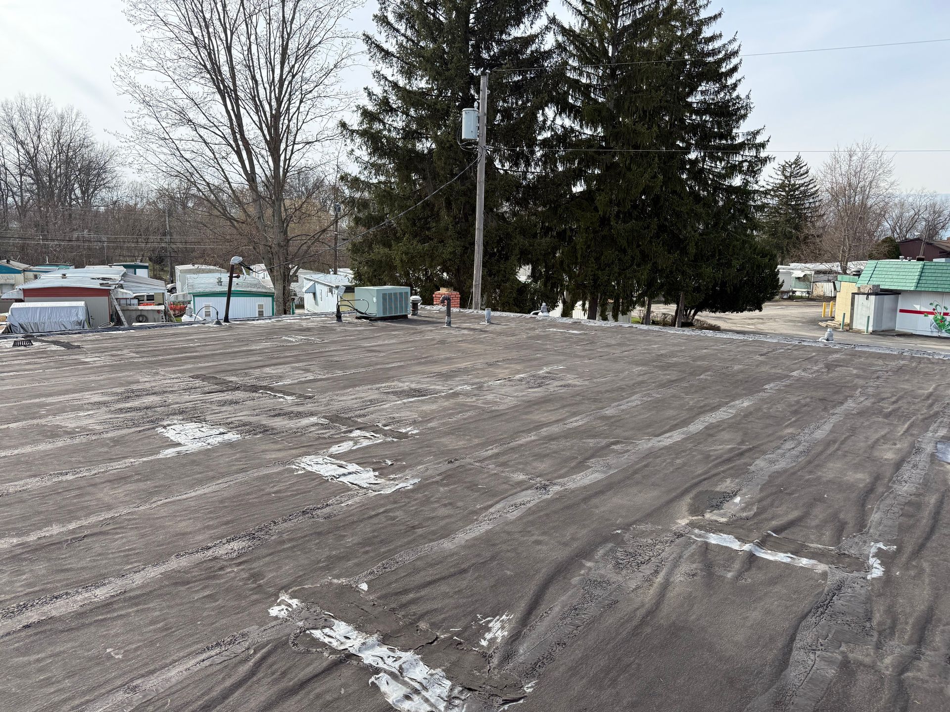 Aging commercial flat roof showing membrane wear, repairs, and maintenance concerns on building