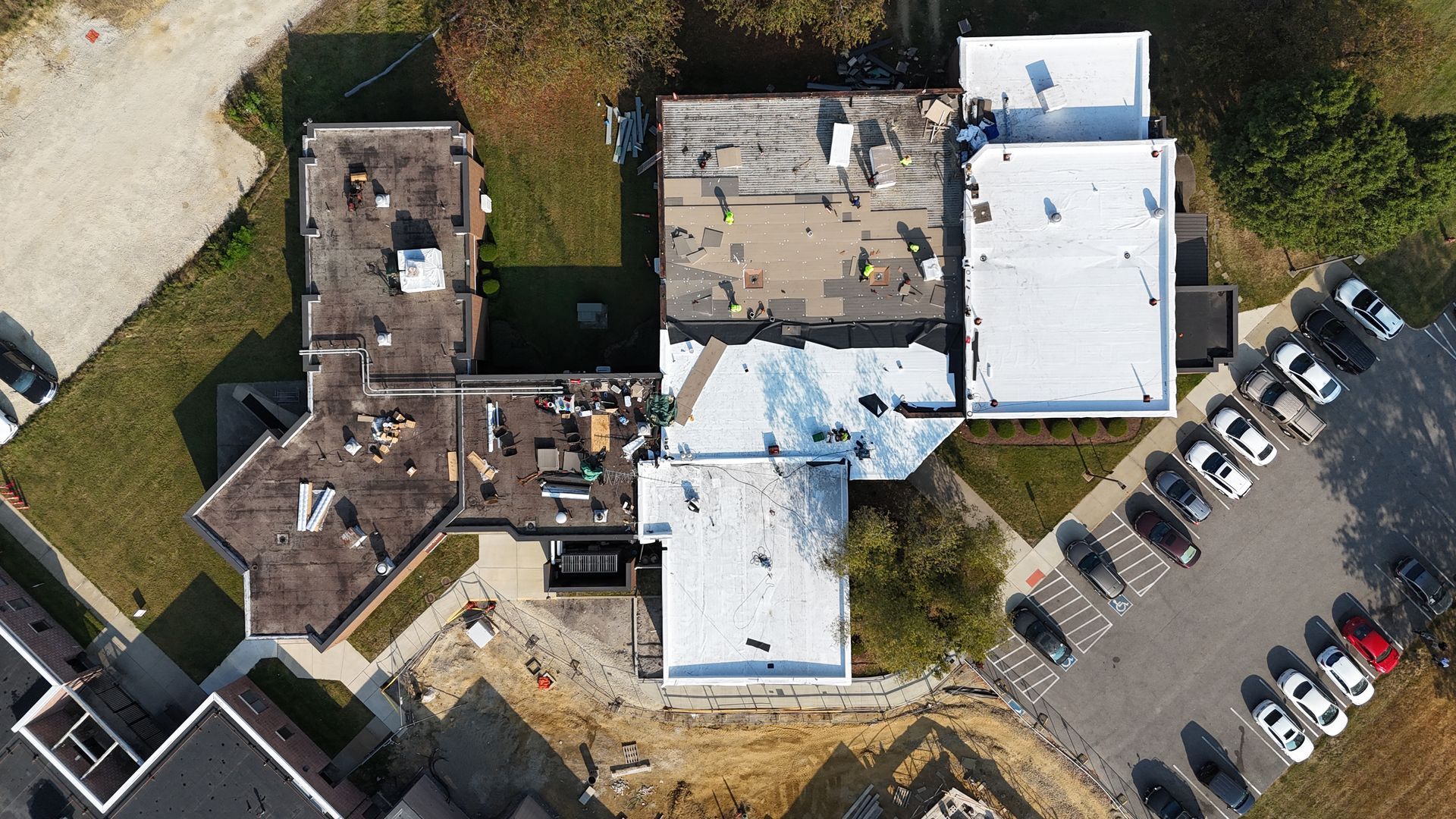 A worker on a ladder installing gutters against a blue sky.