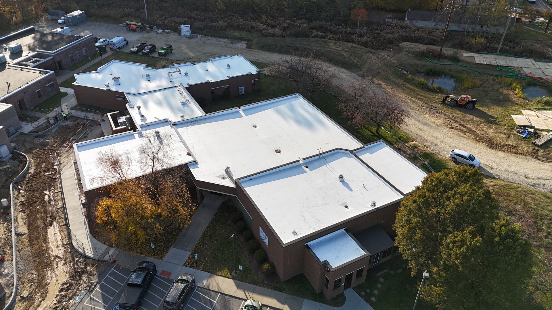 Light blue house with a blue metal roof, white garage door, and green lawn. A blue tarp lies on the driveway.