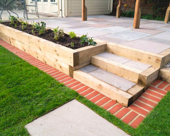 A wooden planter with steps leading up to a patio.