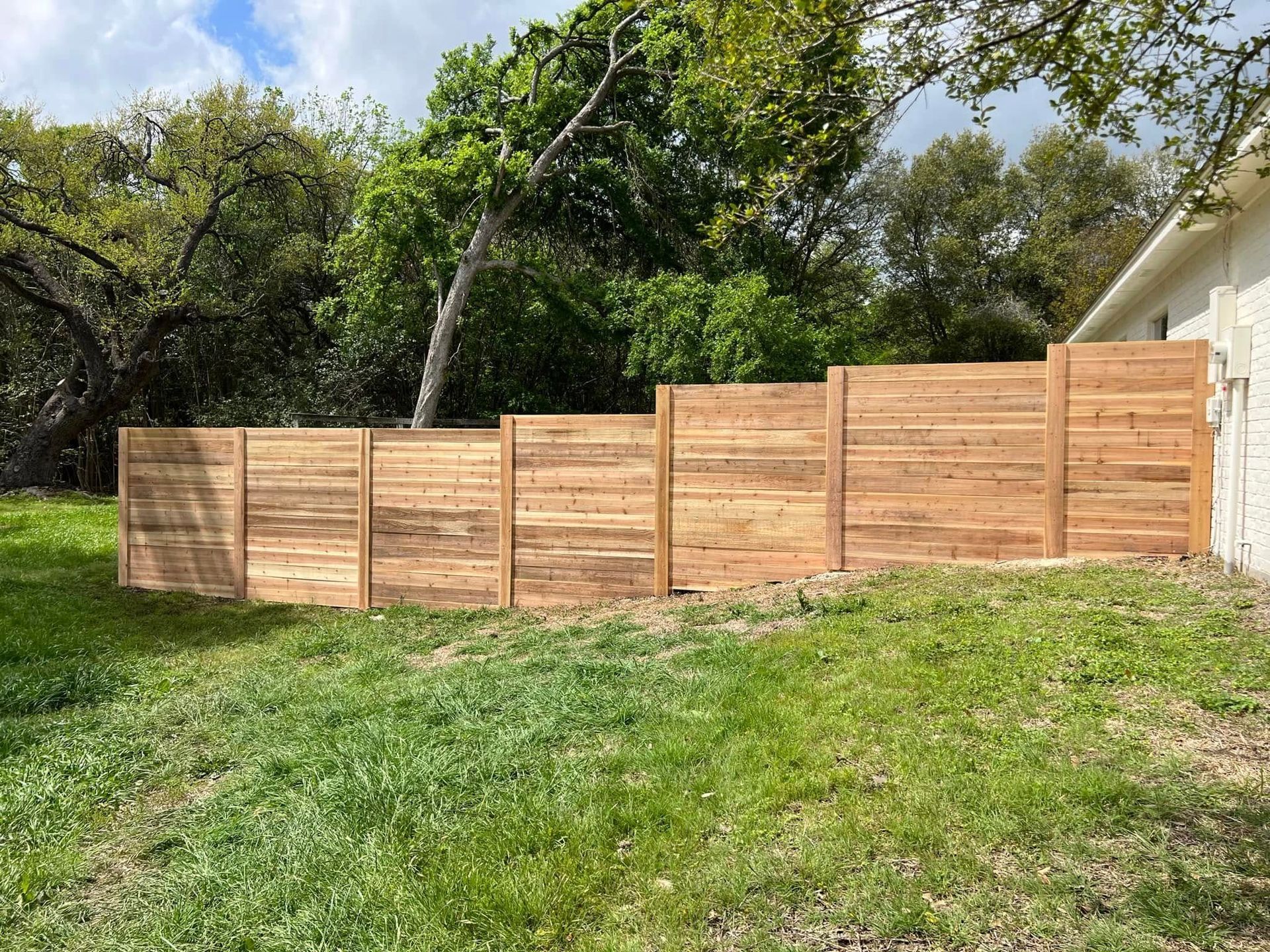 A wooden fence is in the backyard of a house.