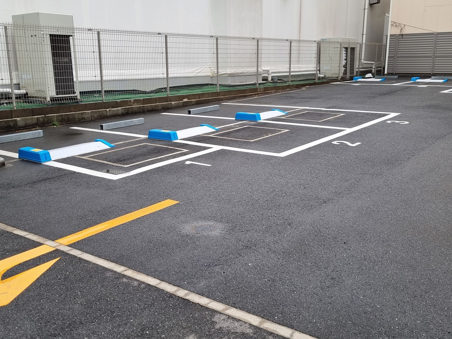 parking asphalt services with marked parking spaces, smooth asphalt surface and safety barriers.