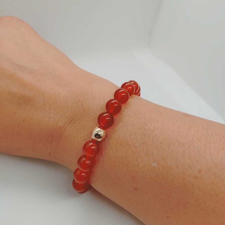 Armband van carneoolkralen met een goudkleur tussenkraal geregen op elastiek.