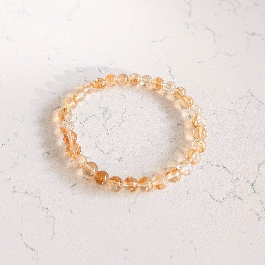 Een close-up van een armband met citrien kralen op een wit oppervlak.