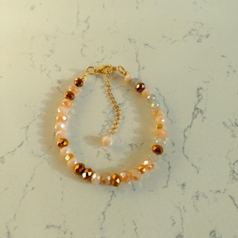 Luxe armband met goudkleur sluiting met verlengkettinkje van facetkralen in roze en bruine tinten.