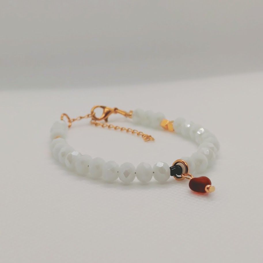 Romantische armband van witte 6 mm facetkralen met een rode hartjesbedel en een gouden stainless steel sluiting met kettinkje
