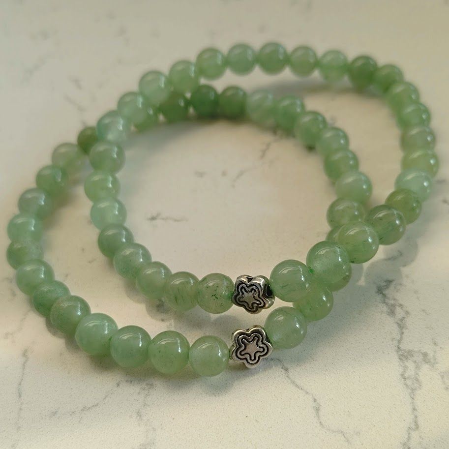 Armband van groene aventurijnkralen op elastiek geregen met een zilverkleur bloemkraal.