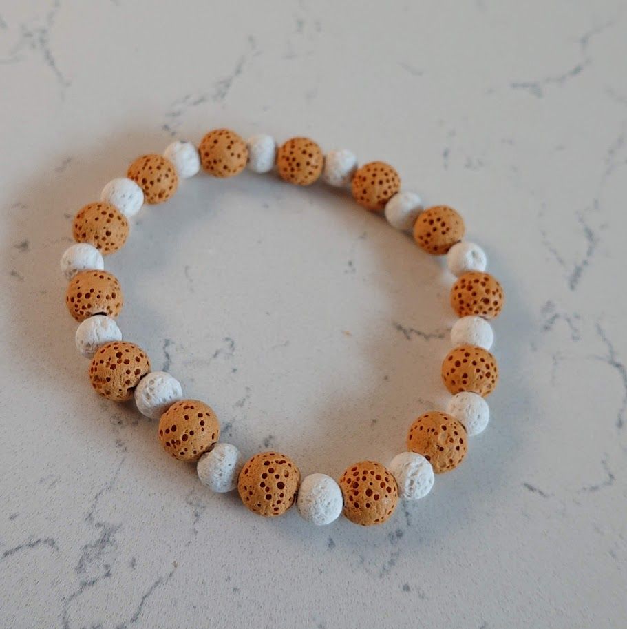 Mooie armband van lavasteenkralen in de kleuren caramel en wit. Geschikt voor aromatherapie.