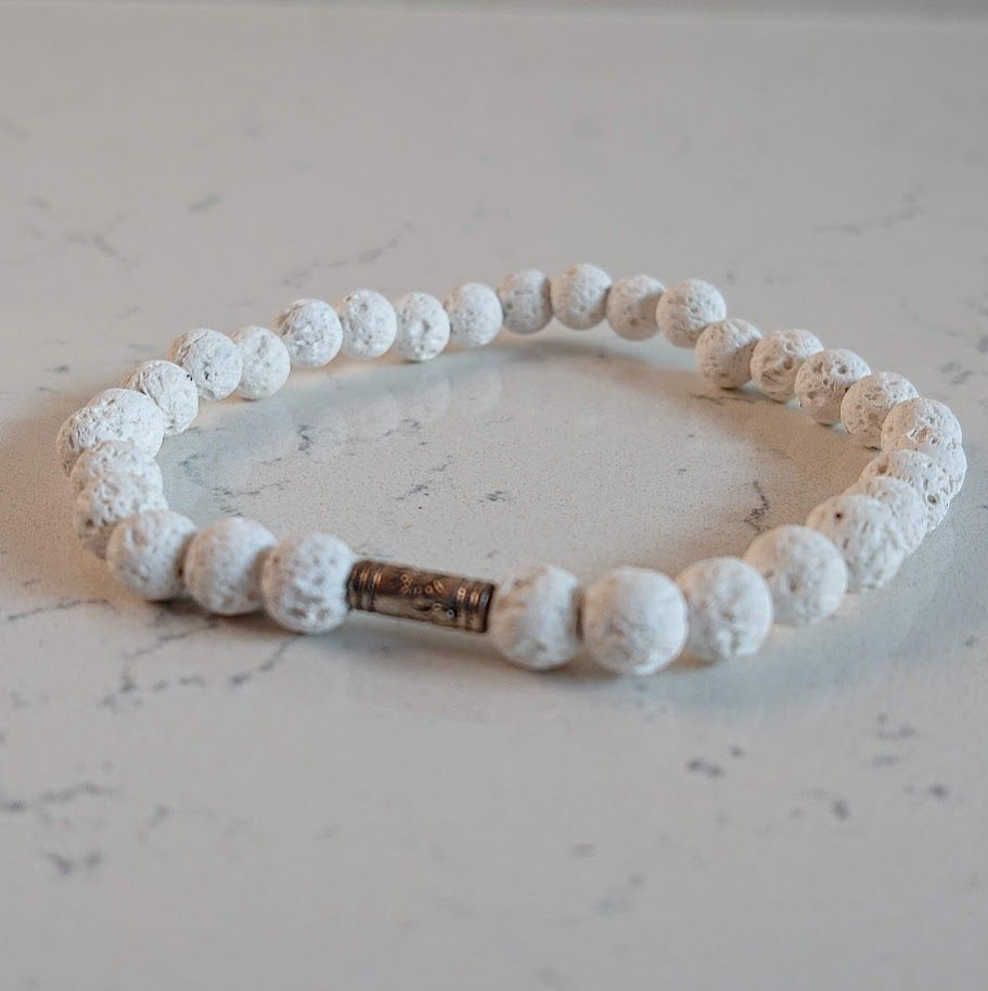 Mooie armband van witte lavasteenkralen met een zilveren tussenkraal met een zonnetje. Geschikt voor aromatherapie.