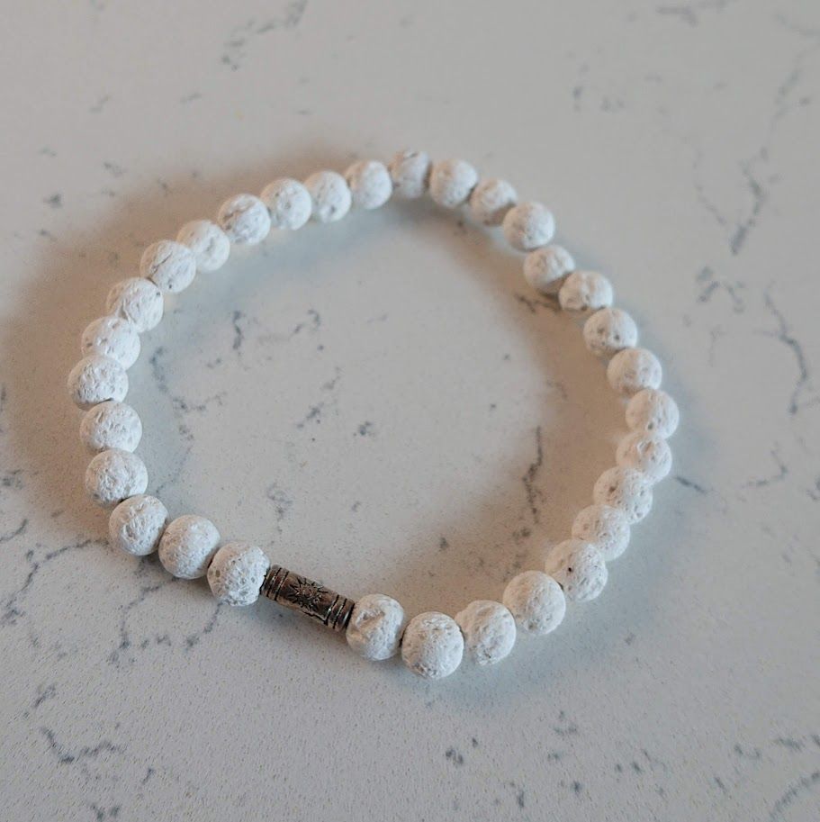 Mooie armband van witte lavasteenkralen met een zilveren tussenkraal met een zonnetje. Geschikt voor aromatherapie.