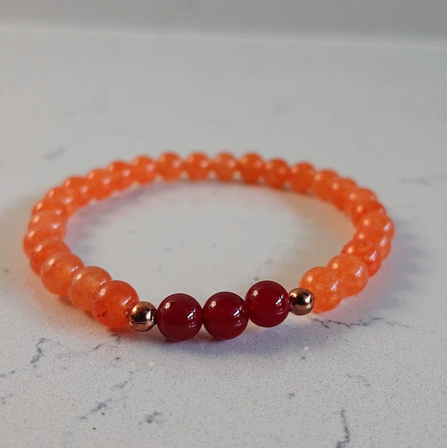Armband op elastiek van 6mm perzik aventurijn en carneoolkralen en kleine gouden stainless steel tussenkraaltjes
