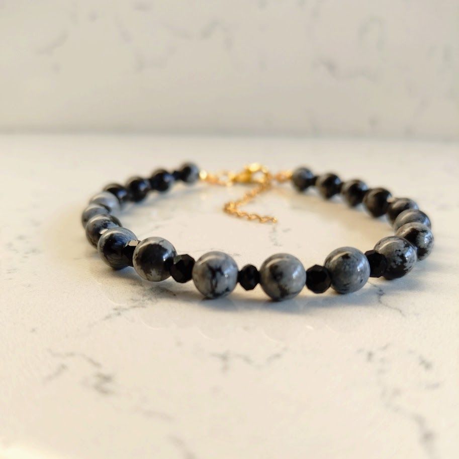 Chique armband van snowflake obsidiaan kralen van 6mm met zwarte facettussenkralen van 4mm en gouden stainless steel sluiting